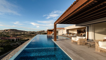 Partially covered outdoor lounge area with infinity pool and a view of the other villas in the Los Cabos area.