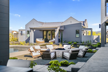 Outdoor lounge area of Bennett with pool and fire pit with white cushioned chairs arranged. 