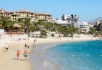 Tourists play in the sand near the shoreline of Medano Beach, a popular thing to do in Cabo.