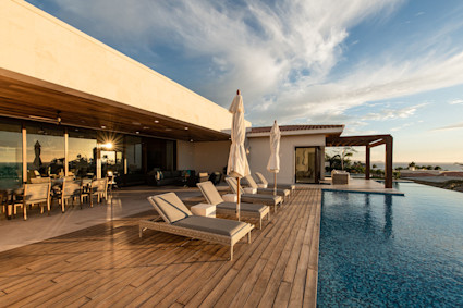 A modern infinity pool with a wooden deck at dusk at Palmilla in Cabo, Mexico, showcasing a private outdoor oasis.