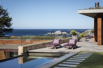 Outdoor pool with lounge chairs next to the ocean