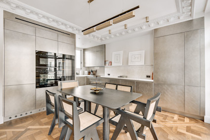 A sophisticated Parisian dining area with crown molding and parquet flooring, illustrating the blend of culinary culture and luxury real estate in the heart of French gastronomy.