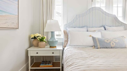 A bedroom with a white bed and a bedspread featuring blue and white stripes