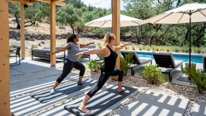 Two women doing a yoga pose in an outdoor terrace