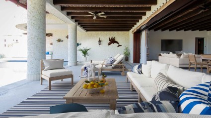 A sleek and modern design living room at a Cabo second home with doors opening to a spacious private terrace