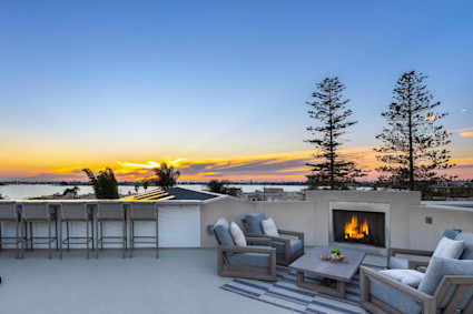 Sail Bay in San Diego features a rooftop patio at dusk with a fireplace and water views, echoing the exclusive ambiance that is signature to La Jolla during high-profile events.