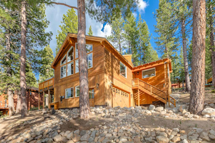 Exterior of Nestled Pines with large pine trees scattered around the property. 