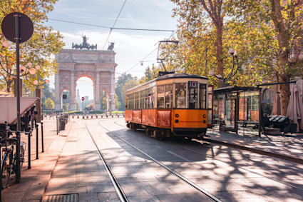 A cable trolley stopping at a bus stop on a road in the city of Milan. 