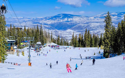 Skier in Aspen cutting through fresh powder on a wide, groomed run, a favorite activity when weighing the appeal of Vail vs. Aspen.