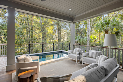 The sunroom with a pool and wood ceiling at Oyster Rake creates a private haven for relaxation, blending indoor elegance with outdoor views in one of Kiawah Island’s sought-after homes.
