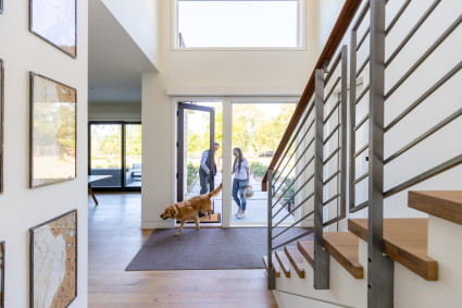 Two owners and their dog enter the doorway of a second home