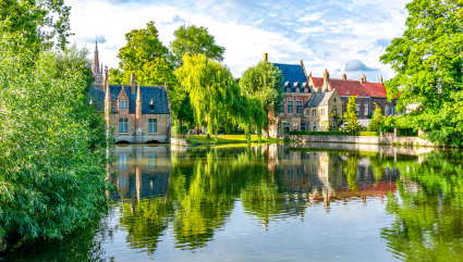 Stone buildings sit at the edge of a canal in Bruges, one of the best vacation spots for couples. 