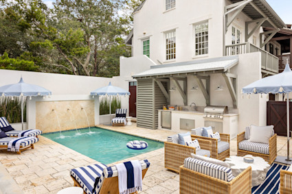 luxurious outdoor patio and pool area ideal for social gatherings in 30A, featuring an inviting lounge, grilling station, and water feature under the Florida sun