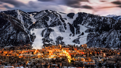Aspen city lights at dusk against the snow-covered mountain.