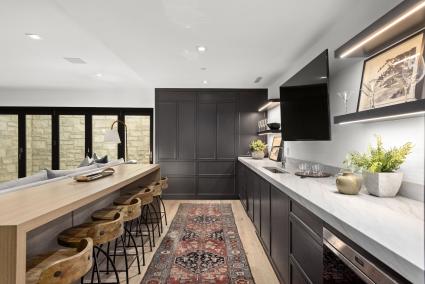 A kitchenette in a home theater with bar seating and a wine fridge.