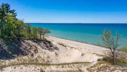 The blue water of Lake Michigan is visible from the top of a dune at Indiana Dunes National Park, one of the best beaches for kids in the Midwest.