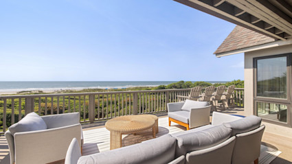 A beachside deck with modern furnishings captures the island’s seamless indoor-outdoor lifestyle and refined social spaces.