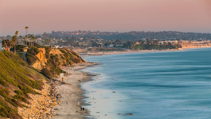 A photo shows a cliffside, beach, and ocean from one of the best neighborhoods in San Diego.

