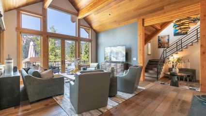 Spacious, rustic living room of a Olympic Valley second home with high ceilings and an views of the deck and lake