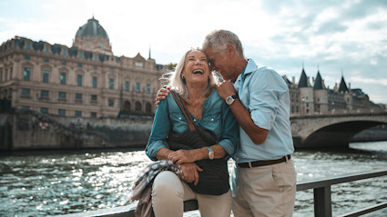 A photo about the best places to retire in Europe shows retirees laughing by the water.