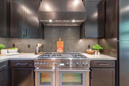 a kitchen with black cabinets and stainless steel stove