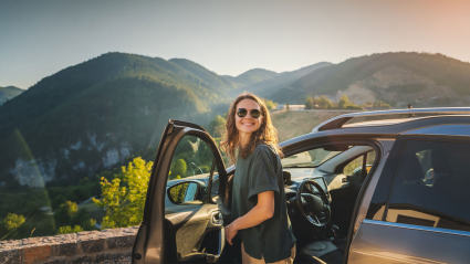 A person steps out of their car while enjoying the scenery of one of the best destinations for solo travelers