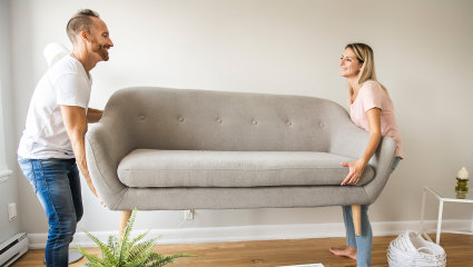 A husband and wife move a new couch into the living room so they can have a happier home.