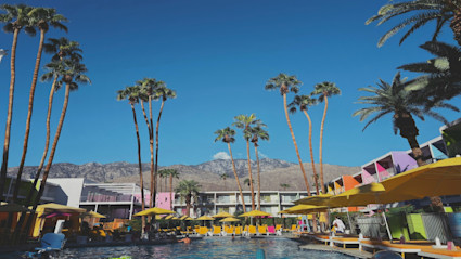 Palm Springs poolside scene with yellow umbrellas and mountain views, a preview of slower afternoons and golden-hour swims during a fall escape.