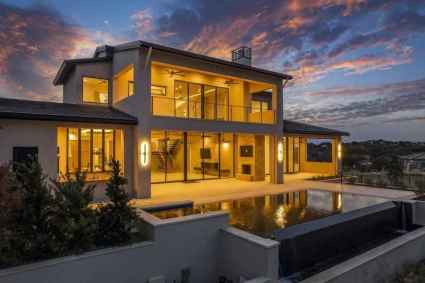 A contemporary vacation home in Horseshoe Bay, TX with a pool reflecting the vibrant colors of a beautiful sunset