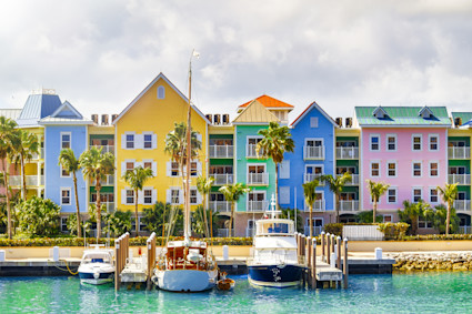 Costal harbor with several boats anchored in front of a row of colorful buildings. 