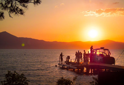 People board a boat as the sun sets over Lake Tahoe