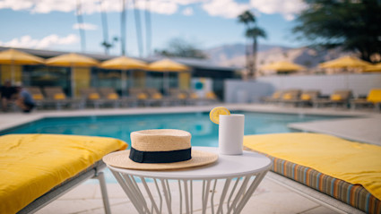 This serene poolside setting in Palm Springs, CA, features lounge chairs, yellow umbrellas, and a breathtaking mountain backdrop under a partly cloudy sky. The scene radiates relaxation and warmth, making it an ideal visual representation of winter wellness and rejuvenation in a luxury desert destination.
