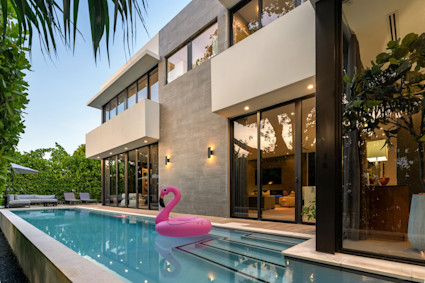 Pool area with exterior lights on with a pink flamingo floatie in the water