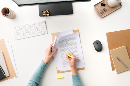 Person highlighting document at desk