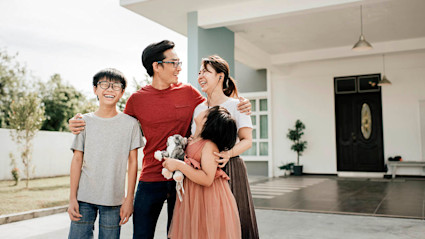 A smiling family stands in front of their new home, after deciding it was time to buy a house.