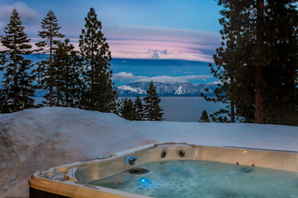 A bright living room with a fireplace and water views at Lakeridge shows how Tahoe interiors can support rest, reading, and unhurried evenings after outdoor time.