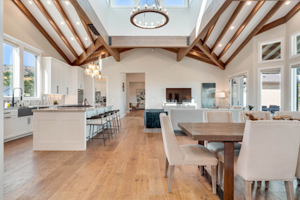 Elegant dining room with a high vaulted ceiling, chandelier and double-sided fireplace in a Napa Valley modern farmhouse, ideal for festive holiday dinners.