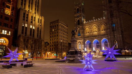 A brightly lit cathedral is visible from a snow-covered square in Montreal, one of the best vacation spots for couples.