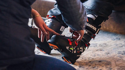 A Ski Butler representative helping a customer in to a pair of ski boots.