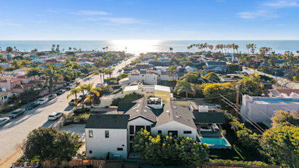 A scenic aerial view of La Jolla, CA, showcasing modern homes, palm-lined streets, and the sparkling Pacific Ocean. The sunlit coastal setting captures the luxurious, exclusive vibe that the La Jolla Concours d'Elegance embodies, setting the stage for a high-end automotive event by the sea.