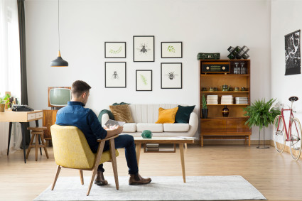 A man sits in a living room that is styled in a Mid-Century Modern way, one of the most popular types of interior design in 2022.