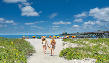 Image of two women walking on the shore of Folly Beach. 
