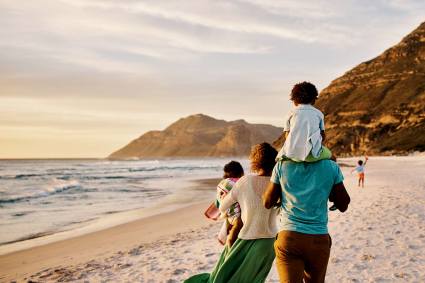 A family walks on the sand at one of the best beaches for kids in the U.S. 