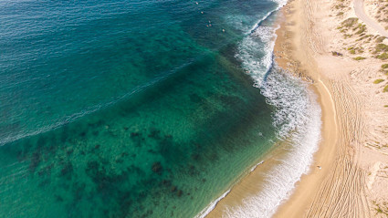 A stock image shows the ocean and beach of East Cape.
