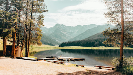 A serene mountain lake in Vail, surrounded by pines and mountains, highlighting the region’s natural appeal for bird watching and fall exploration.