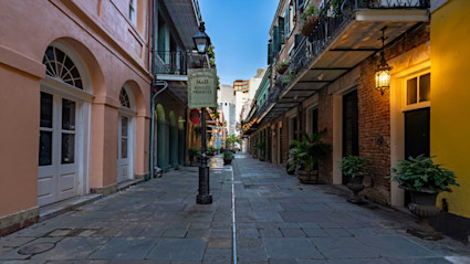 A charming pedestrian alleyway in Charleston, SC, with cobblestone paving, peach-colored walls, and a glowing lantern that evokes a moody, historic ambiance perfect for Halloween. The atmospheric setting captures the city's old-world charm and mysterious allure, ideal for highlighting an autumnal weekend filled with historic tours.