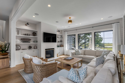 Victory Bay’s bright, open living room is an example of Kiawah’s coastal elegance—custom built-ins, a fireplace, and windows that draw in the landscape, set in a location just minutes from beach and golf.