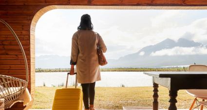 A woman wheels her suitcase into her lake house after answering the question, “Can I afford a second home?” with the help of a second home calculator.