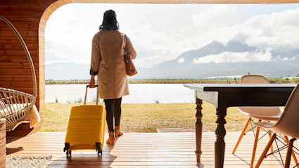 A woman wheels her suitcase into her lake house after answering the question, “How much does a second home cost?” with the help of a second home calculator.