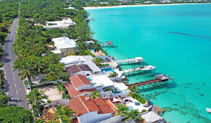 Aerial view of coastal homes in the Bahamas with vibrant turquoise water.